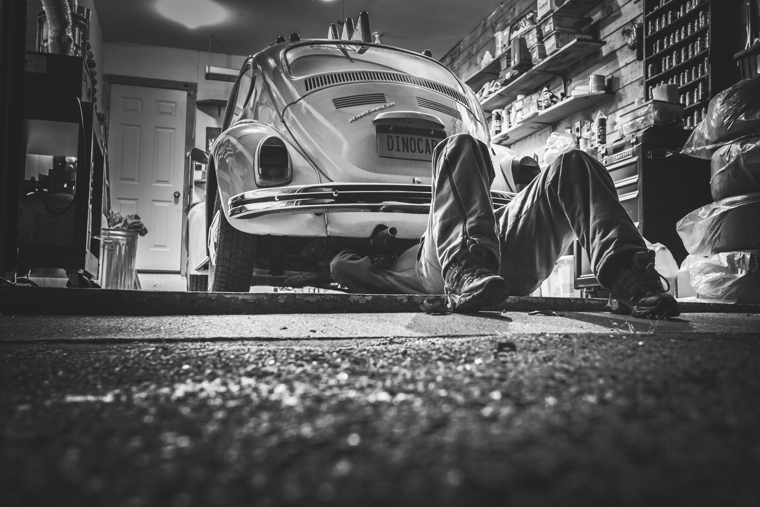 Safety Precautions That Every Auto Mechanic Should Adhere To Picture: Black and white image of mechanic working under a Beetle car in a garage
